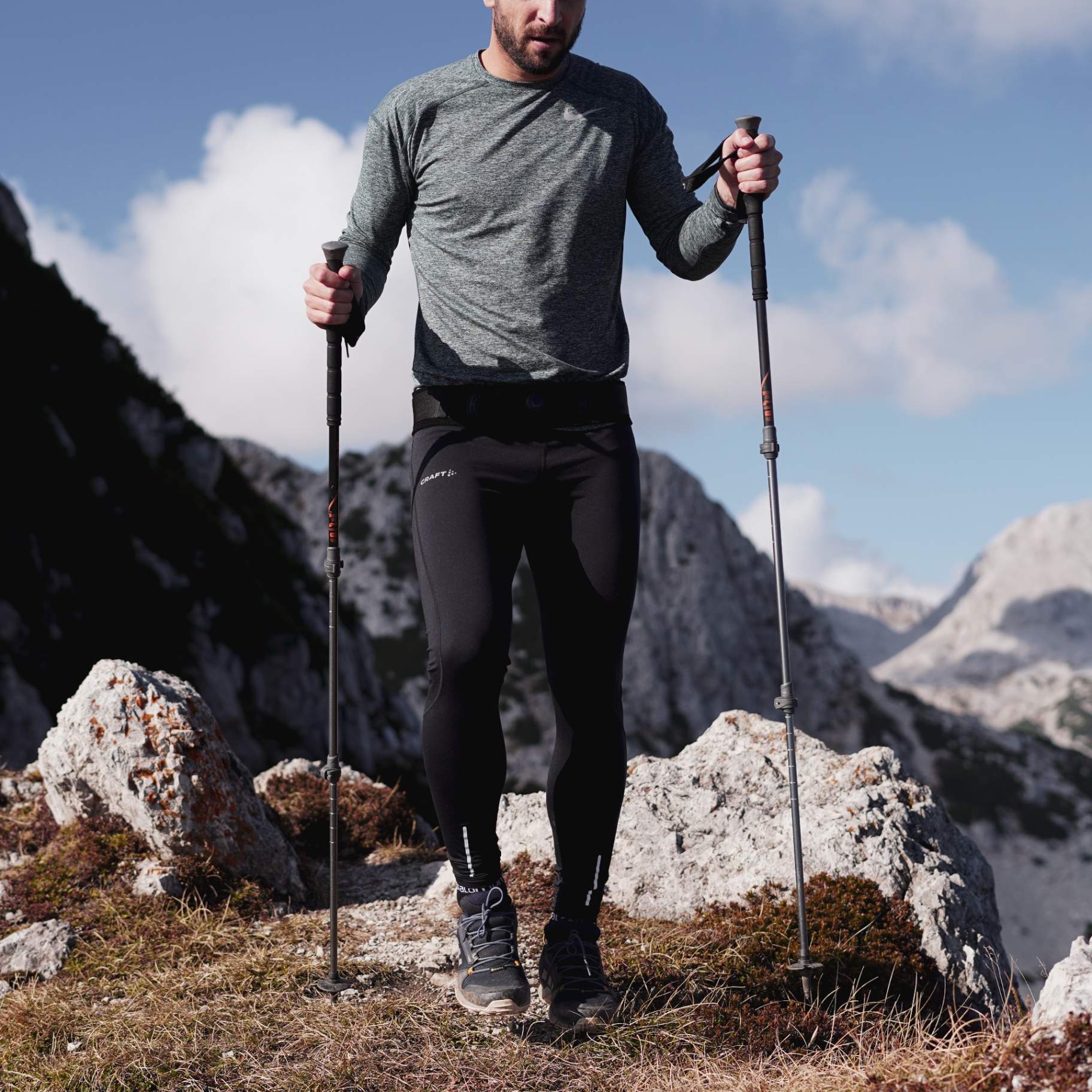 Man wearing the Levo Belt hiking in the mountains with trekking poles